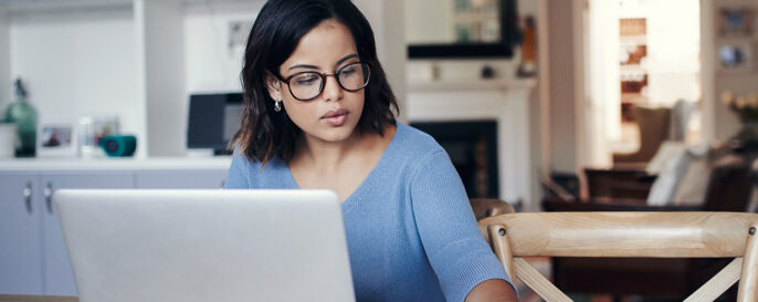 Woman working at computer, reaching for calculator