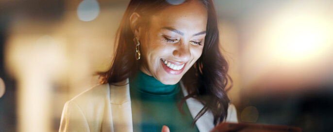 Woman smiling while looking at digital tablet