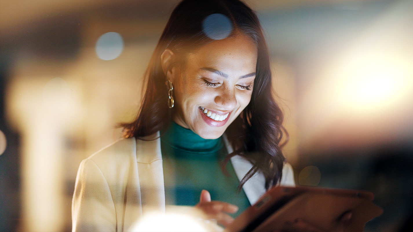 Woman smiling while looking at digital tablet