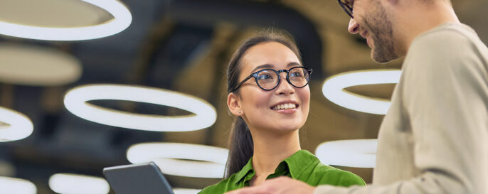 Young female intern with digital tablet in hand, discussing work information with male mentor